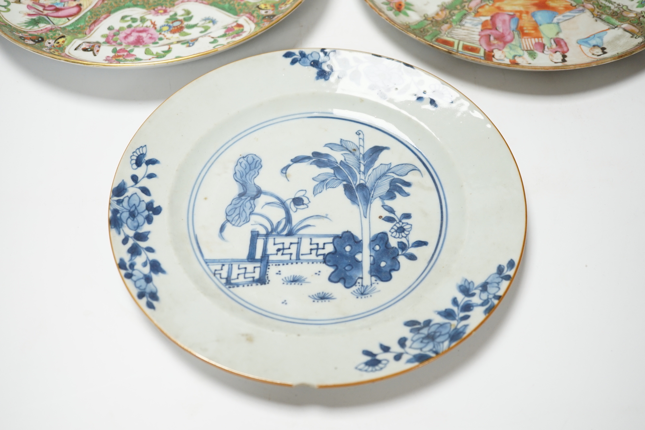 Two 19th century Chinese famille rose plates and an 18th century blue and white plate, 24cm in diameter